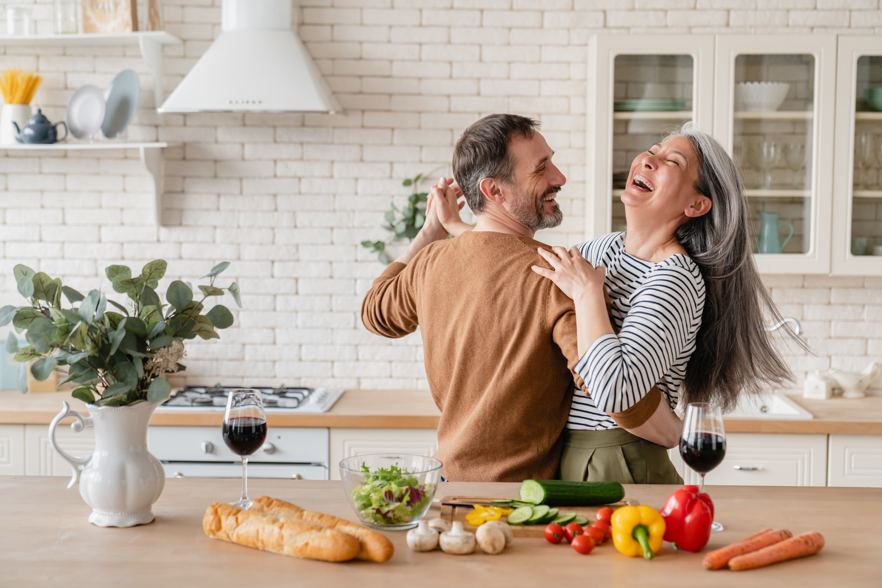 Two adults in the kitchen embracing